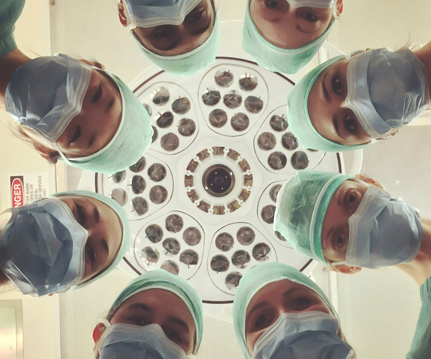 Mehrere Ärzt:innen stehen im Kreis und gucken von oben in die Kamera